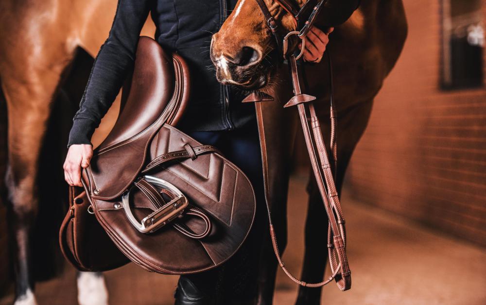 cavalier avec une selle en cuir dans les mains